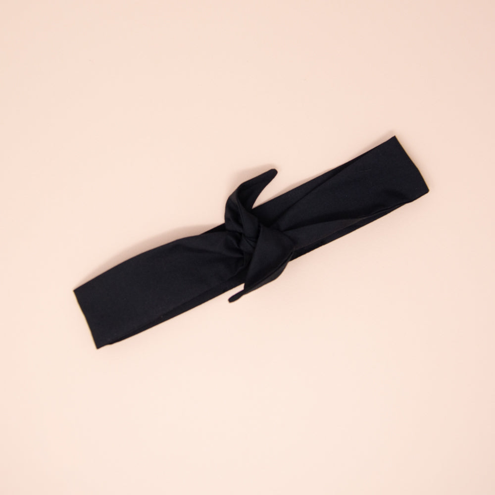 Bandeau à torsader noir, posé à plat et noué